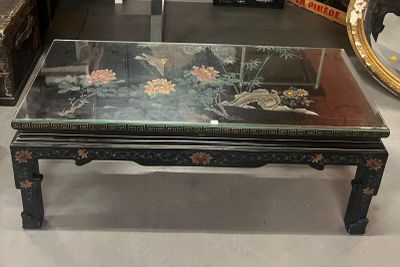 une table basse avec un plateau en verre et un miroir accroché au mur