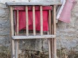 a wooden chair with a red blanket on it next to a stone wall