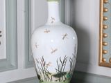 un vase blanc orné de libellules, posé sur une table