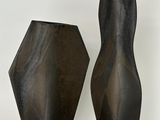 deux vases noirs posés l'un à côté de l'autre sur une surface blanche
