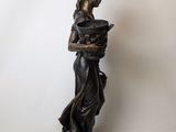 bronze statue of a woman holding a pot on a rock