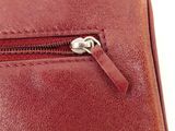 the zipper of a red purse is open on a white surface