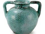 un vase vert posé sur une surface blanche
