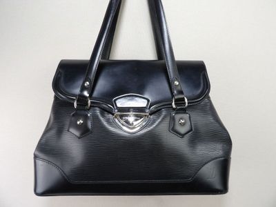 sac à main en cuir noir accroché à un mur, avec un mur blanc en arrière-plan