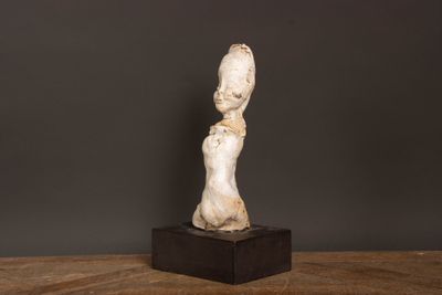 une statue blanche représentant une femme, posée sur une table en bois
