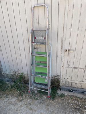 a metal ladder leaning against a white wall next to a building