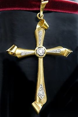 gold and diamond cross pendant on a red velvet necklace