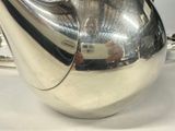 a silver tea pot with a handle on a table