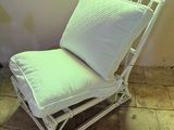 a white wicker chair with a white pillow on it
