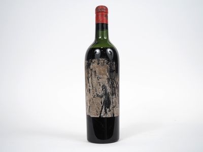 une vieille bouteille de vin rouge posée sur une table blanche