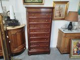 a dresser and a lamp in a room with pictures on the wall