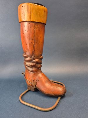 une paire de bottes anciennes en bois posées sur un support et entourées d'une corde
