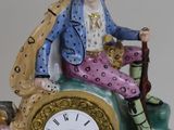 a figurine of a man sitting on top of a clock
