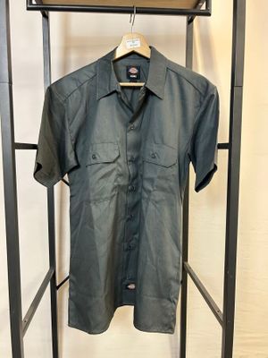 une chemise suspendue à un portant devant un mur blanc