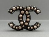a close up of a brooch with pearls on it