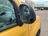 a side view mirror of a yellow truck in a parking lot