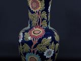 un vase bleu orné d'un motif floral sur fond noir