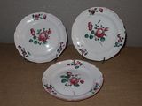 trois assiettes ornées de roses sont posées sur une table