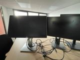 two computer monitors sitting on top of a wooden desk