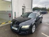 une Audi noire garée devant un immeuble