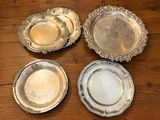 quatre assiettes en argent posées sur une table en bois, dont une est vide et une autre est vide