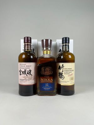 trois bouteilles de whisky sont alignées sur une surface blanche