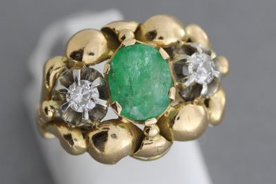 gros plan d'une bague avec une pierre verte entourée de diamants