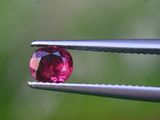 un gros plan d'un diamant rose tenu par une paire de pinces