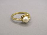 Gros plan sur une bague en or ornée d'une perle