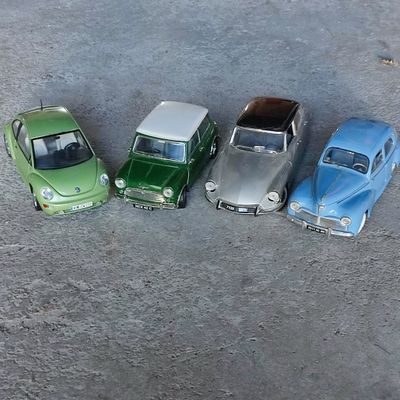 Quatre voitures miniatures sont alignées en rang dans un parking