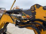 a backhoe of a yellow construction vehicle with a large pipe sticking out of it