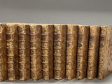 six vieux livres alignés sur une surface blanche