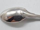 a silver spoon with a spoon handle on a white surface