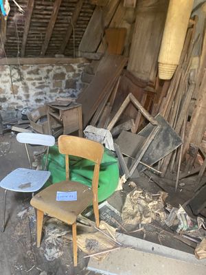 a chair and a table in the middle of a room full of junk
