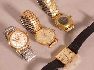 Trois montres différentes sont posées sur une table, avec un bracelet noir.