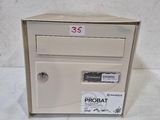 une boîte aux lettres blanche sur laquelle est collé un autocollant noir et rouge
