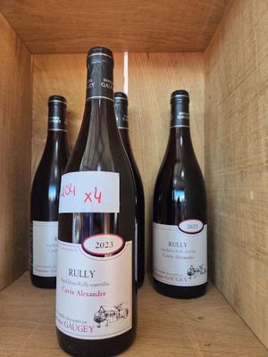 trois bouteilles de vin rouge sont posées sur une étagère dans une caisse en bois