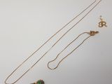 deux colliers en or ornés d'une pierre verte sur un fond blanc