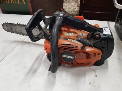une tronçonneuse orange et noire posée sur une table