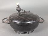 un pot noir surmonté d'un oiseau