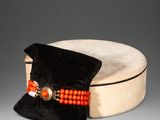 an orange beaded bracelet sits on top of a black velvet bag