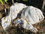 un tas de sacs posé par terre à côté d'une clôture