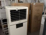 un climatiseur blanc posé dans une pièce où se trouvent de nombreux cartons