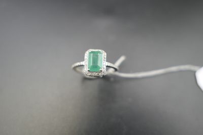 Une bague sertie d'une émeraude et de diamants repose sur une table, à côté d'une souris d'ordinateur