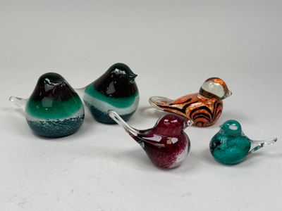 four glass birds sitting on top of each other on a white surface