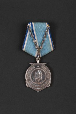 an old medal with a blue ribbon and a silver clasp