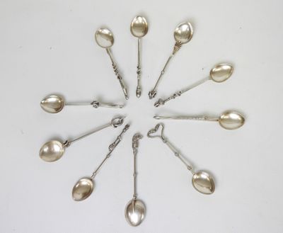 six cuillères en argent disposées en cercle sur une surface blanche