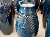 quatre vases bleus posés sur une table recouverte d'une nappe blanche