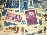 De nombreuses photos anciennes représentant des personnes et des bâtiments sont exposées sur une table.
