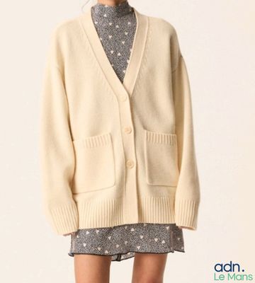 the woman is wearing a white cardigan sweater and a gray dress